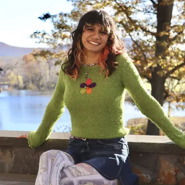 Lia Jacobs '24 sitting outside in front of Paradise Pond