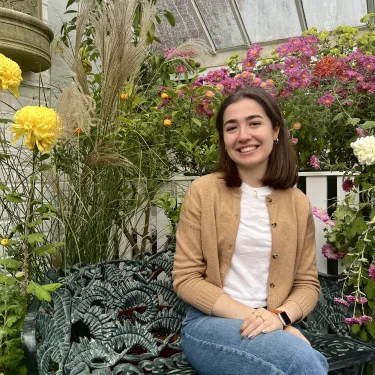Nicole Papageorgiou ’24 sits smiling in Lyman Conservatory