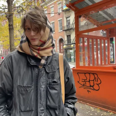 Henne Van Campen ’24 with a scarf and leather jacket outside in the city