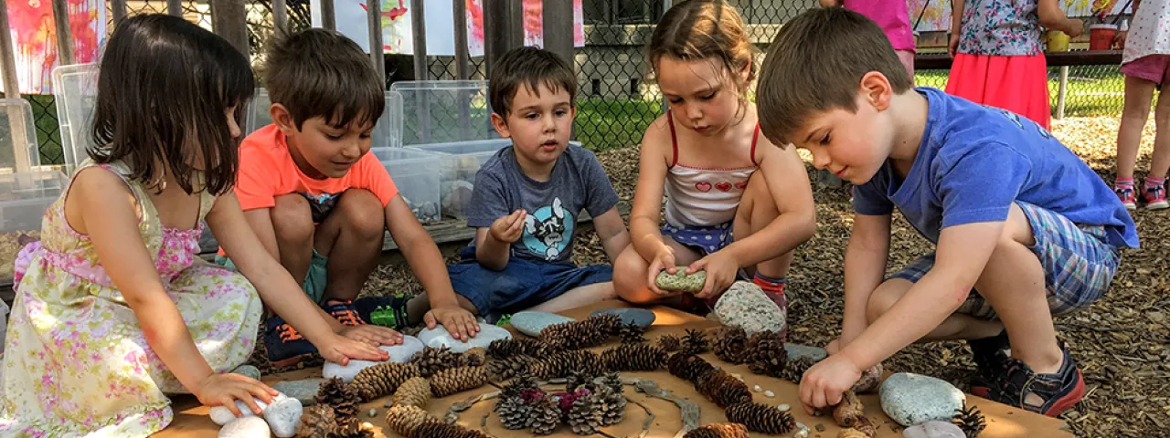 Group of young children making art from pinecones