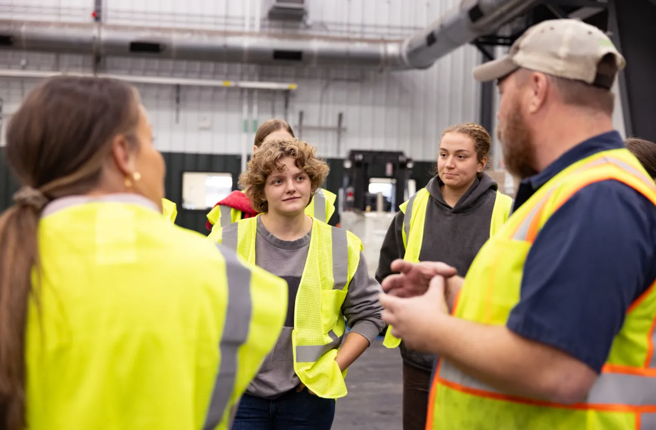 A Smith student looks interested during a tour of Vanguard Renewables, where the entire group wears bright yellow vests