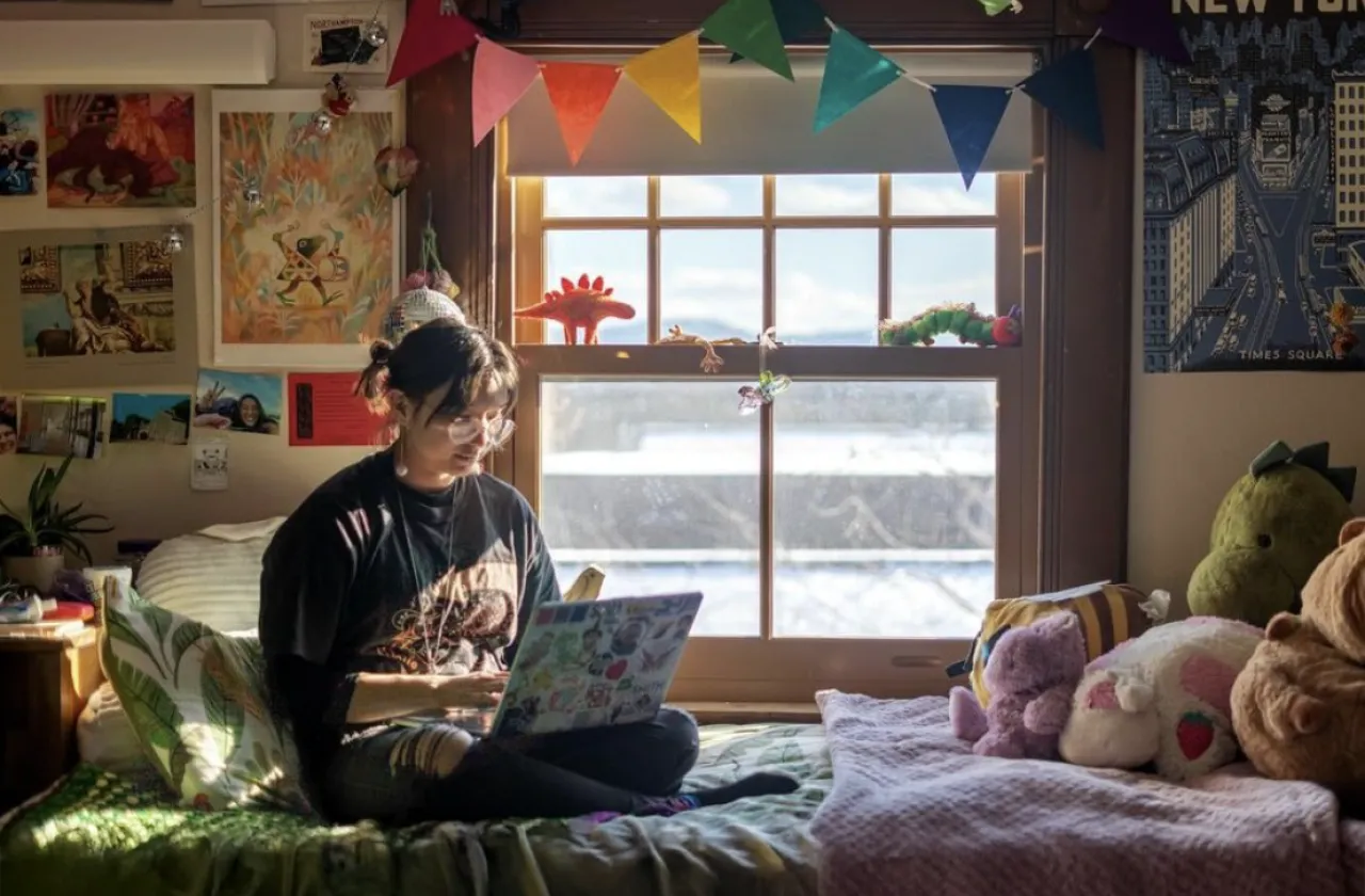 Cloud Osmond sitting on a bed, working on a laptop.