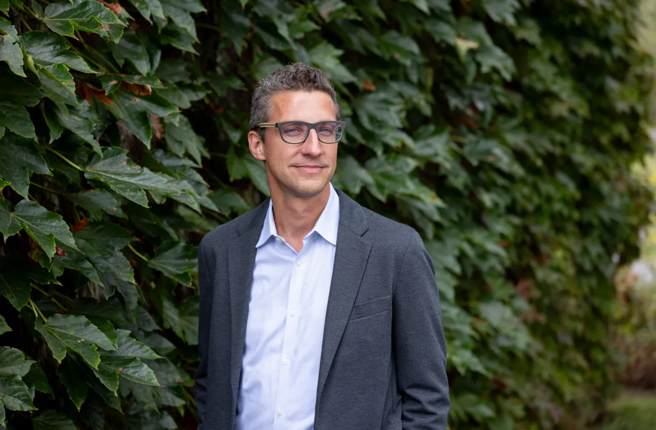 Tim Recuber stands in front of a wall of green leaves.