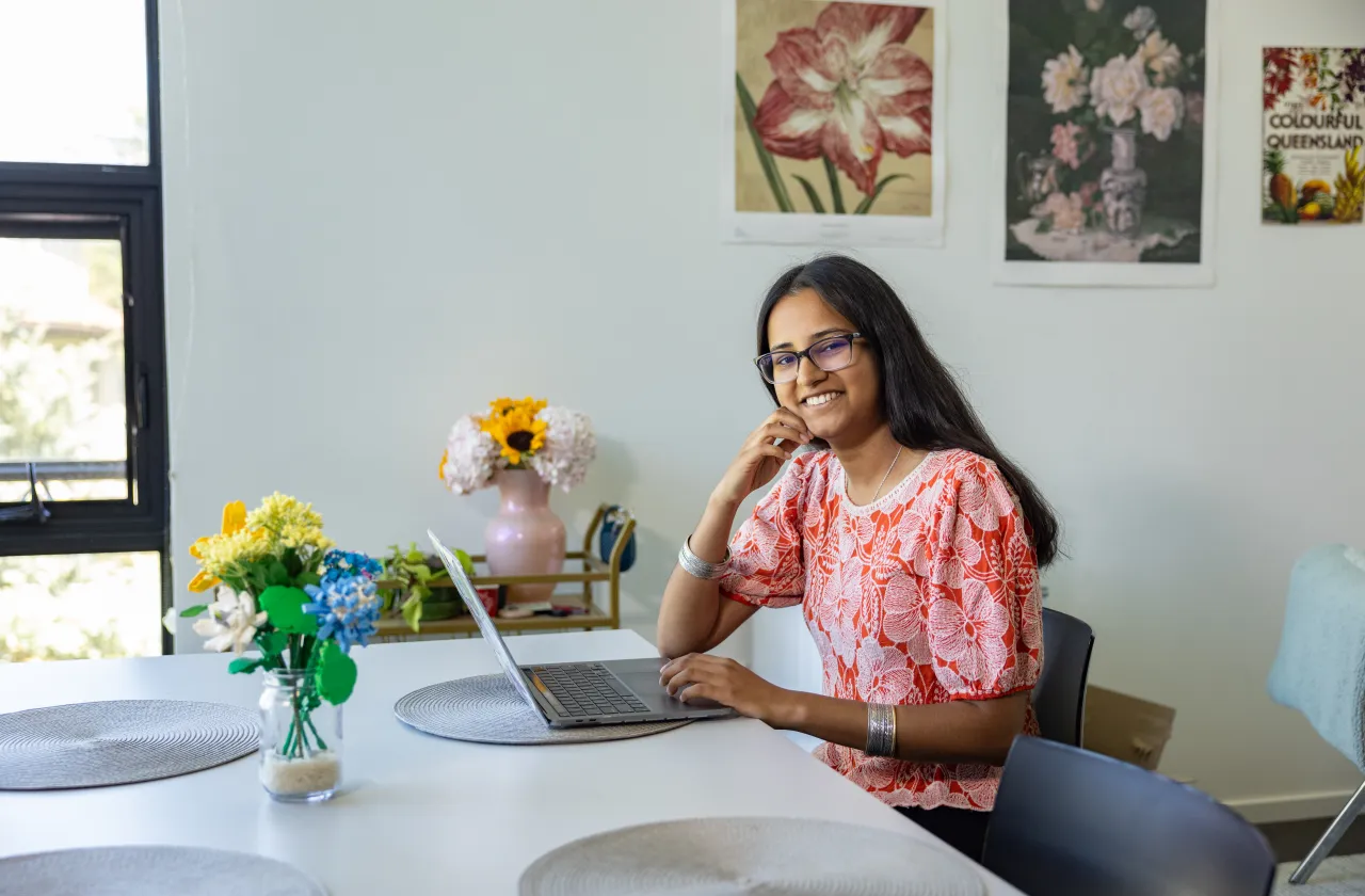 Sirohi Kumar smiles while sitting at a table with her laptop.