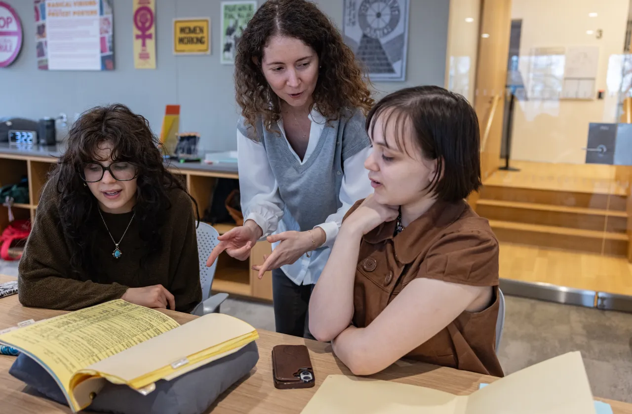 A faculty member talks with two students.