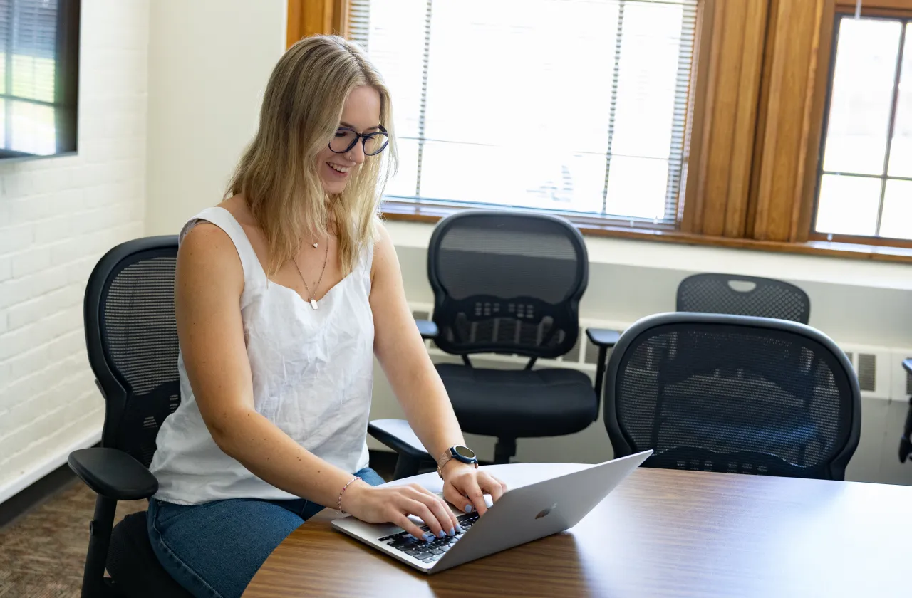 A student smiles at her laptop.