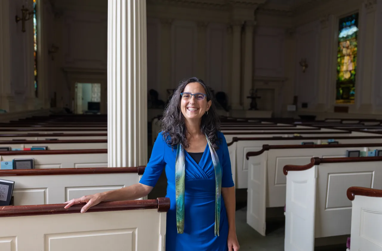 The Rev. Melissa Carvill Zeimer '95 leans on a pew in the Northampton Unitarian Church whose congregation she leads.