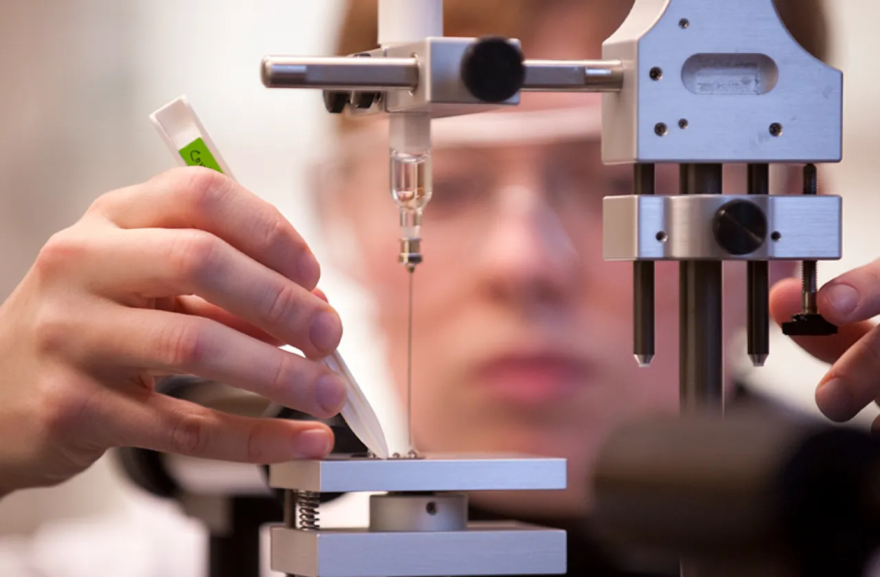 Closeup of a student's hands adjusting a scientific instrument