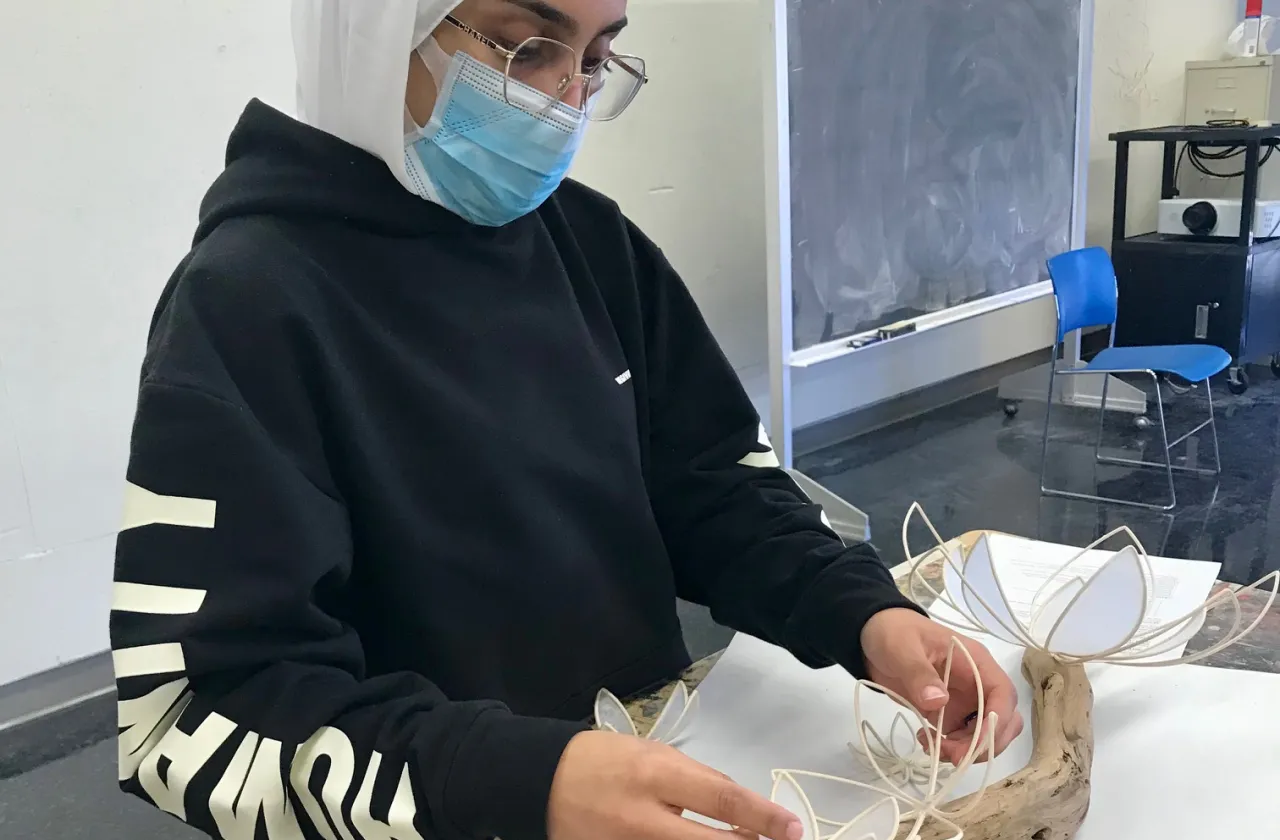 A student creates a sculpture using plant materials.