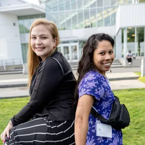 Two women smiling, standing back to back