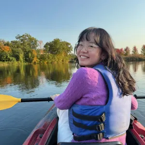 Sherry Li, in a kayak in the fall, looks over her shoulder, smiling