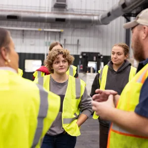 A Smith student looks interested during a tour of Vanguard Renewables, where the entire group wears bright yellow vests