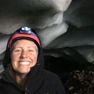 Smith student Molly Peek wears headlamp and stands surrounded by ice