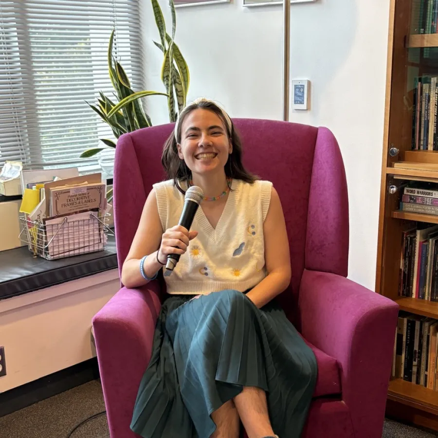 Julia Garnett '28 sits in an armchair with a microphone preparing to host an open mic event