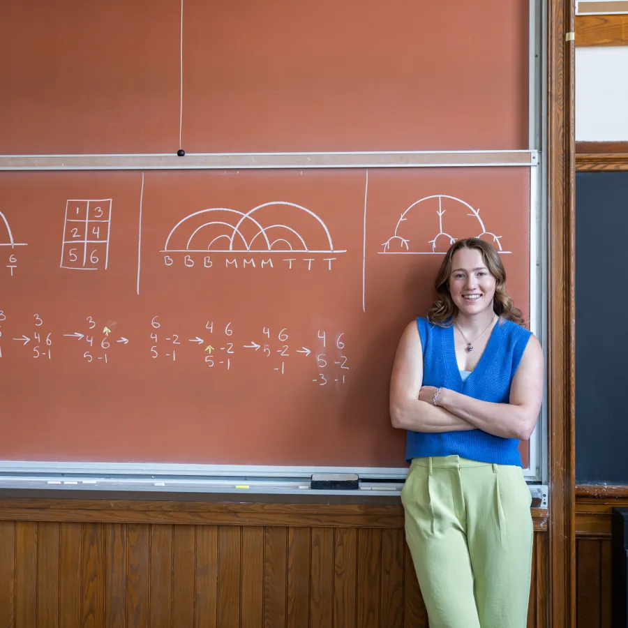 Kerry Seekamp in front of a tan-colored chalkboard.