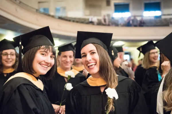 Two smiling people in graduation robes