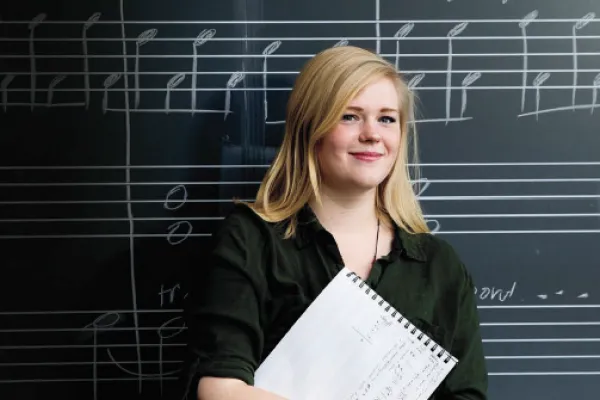 Liberal Arts - Music - A woman stands in front of a blackboard covered in musical notation.