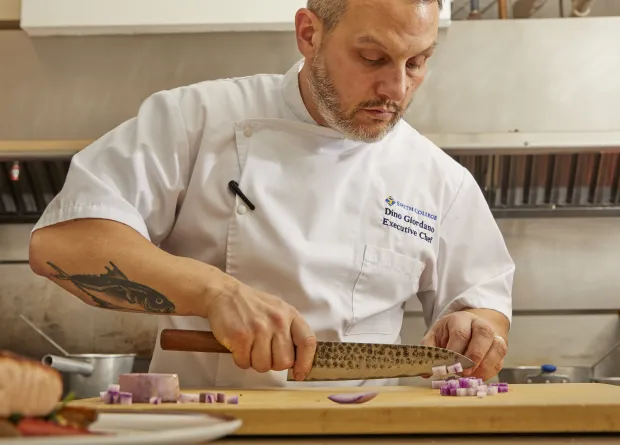 A Smith College chef dicing a red onion.