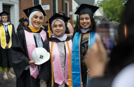 A group of seniors in caps and gowns smile on Commencement Day