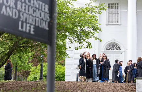 A group of seniors in their gowns pose in front of the Chapel