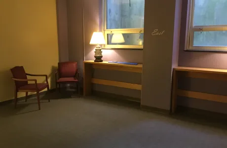 The prayer space in Wright Hall, featuring purple walls with one marked east, red chairs and lamps.