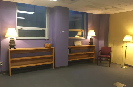 The prayer space in Wright Hall, featuring purple walls with one marked "east," red chairs and lamps.