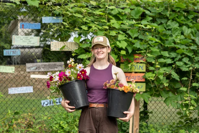 A student carrying two potted plants.