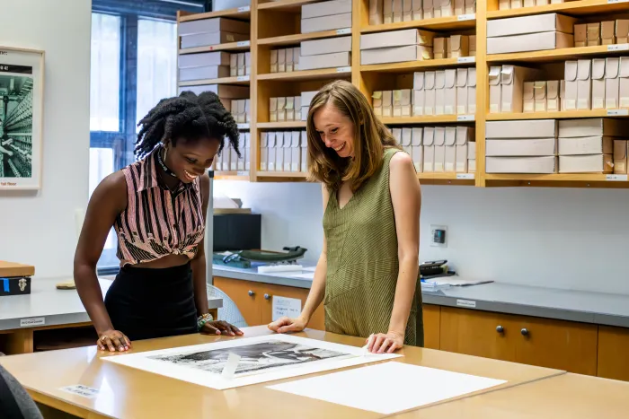 A student and supervisor looking at a photo on a table.