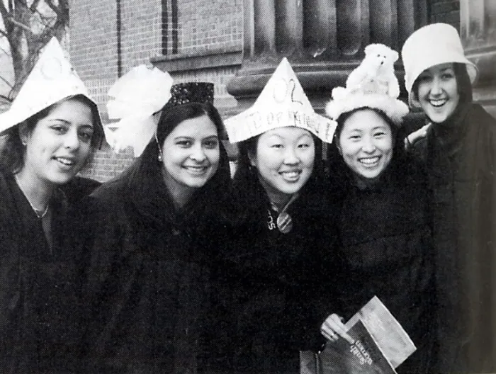 A group of seniors in front of John M. Greene Hall, in hats and gowns.