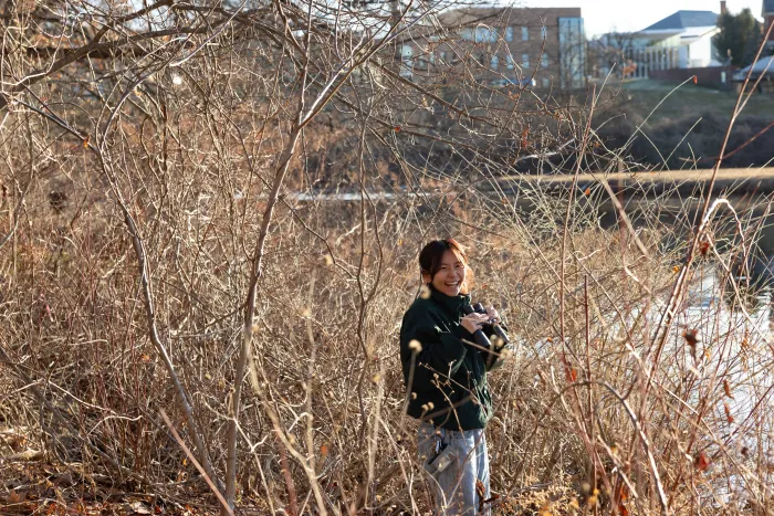 A student laughs while using binoculars to see birds.