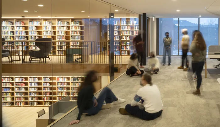 Students sitting on the ground, talking, overlooking another level of the library