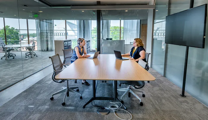 Two people sitting at a table in a collaborative room in Neilson