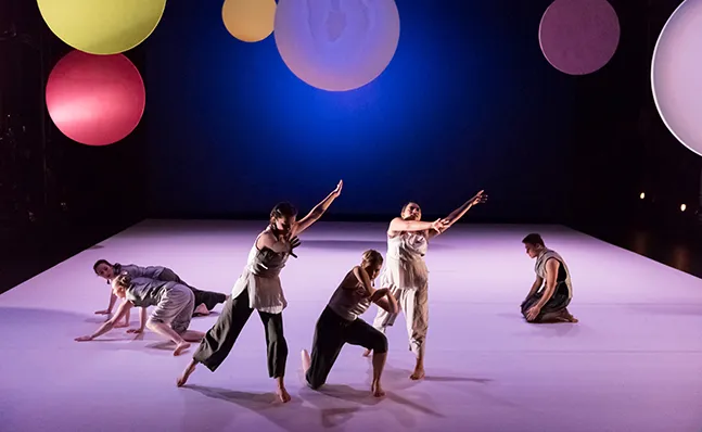 Four dances onstage with a backdrop of colored circles
