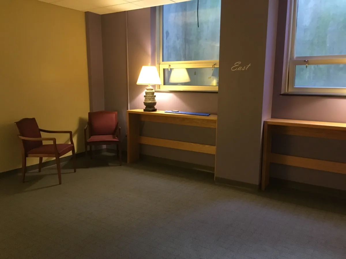 The prayer space in Wright Hall, featuring purple walls with one marked east, red chairs and lamps.