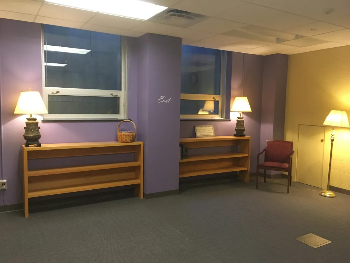 The prayer space in Wright Hall, featuring purple walls with one marked "east," red chairs and lamps.