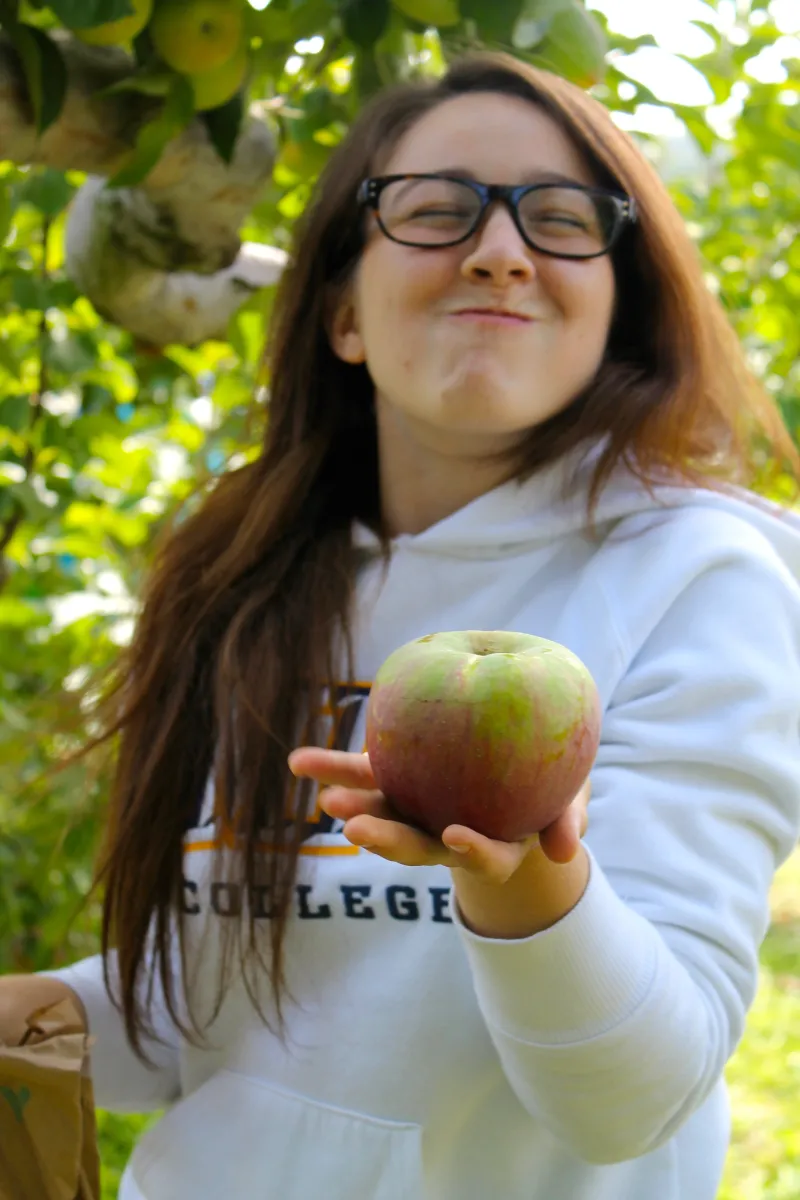 A student smiles holding an apple on Mountain Day in 2014