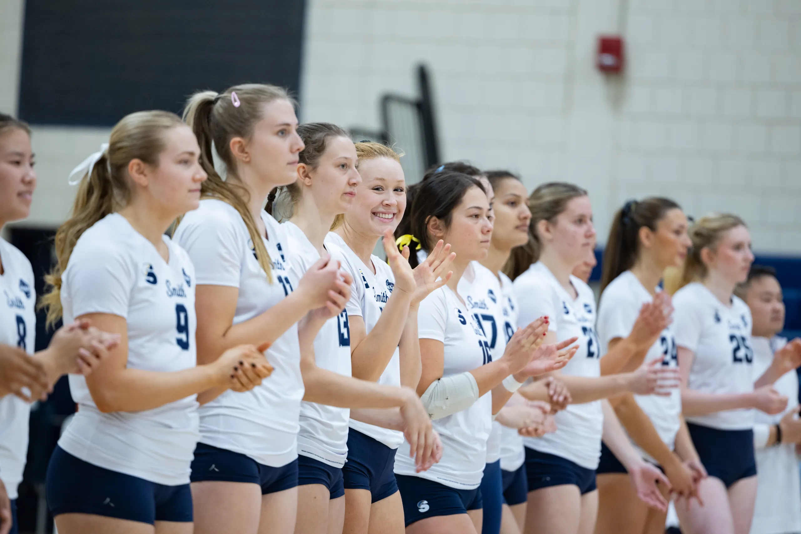 The volleyball team lines up and smiles during a game taking place during Come Home to Smith 2025