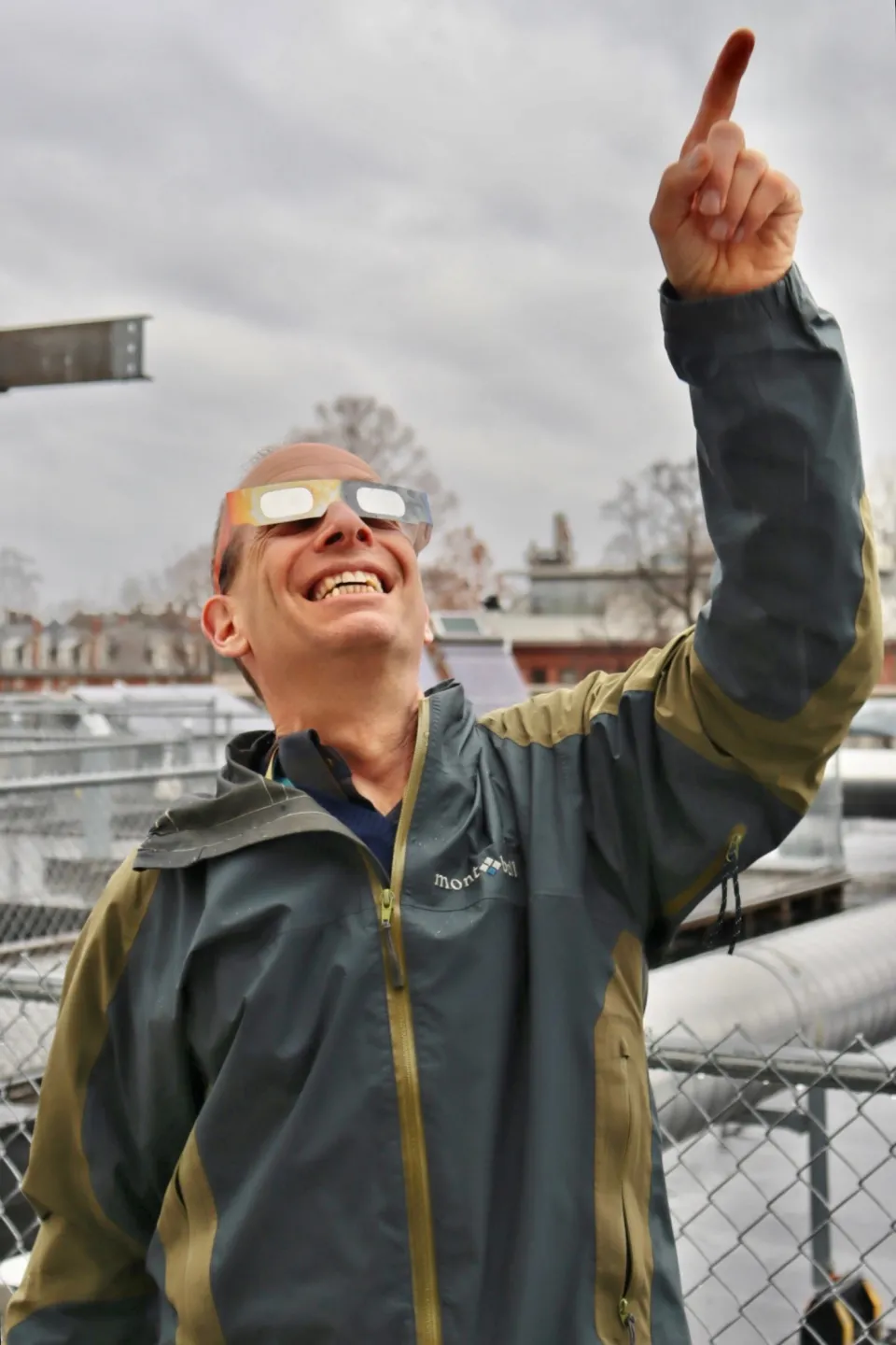 James Lowenthal wearing solar eclipse glasses and pointing into the sky