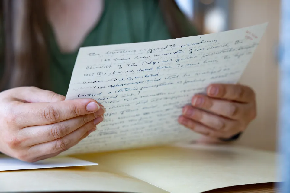 Kady Wilson's hands as she holds a letter written by her great-grandmother in Smith Special Collections