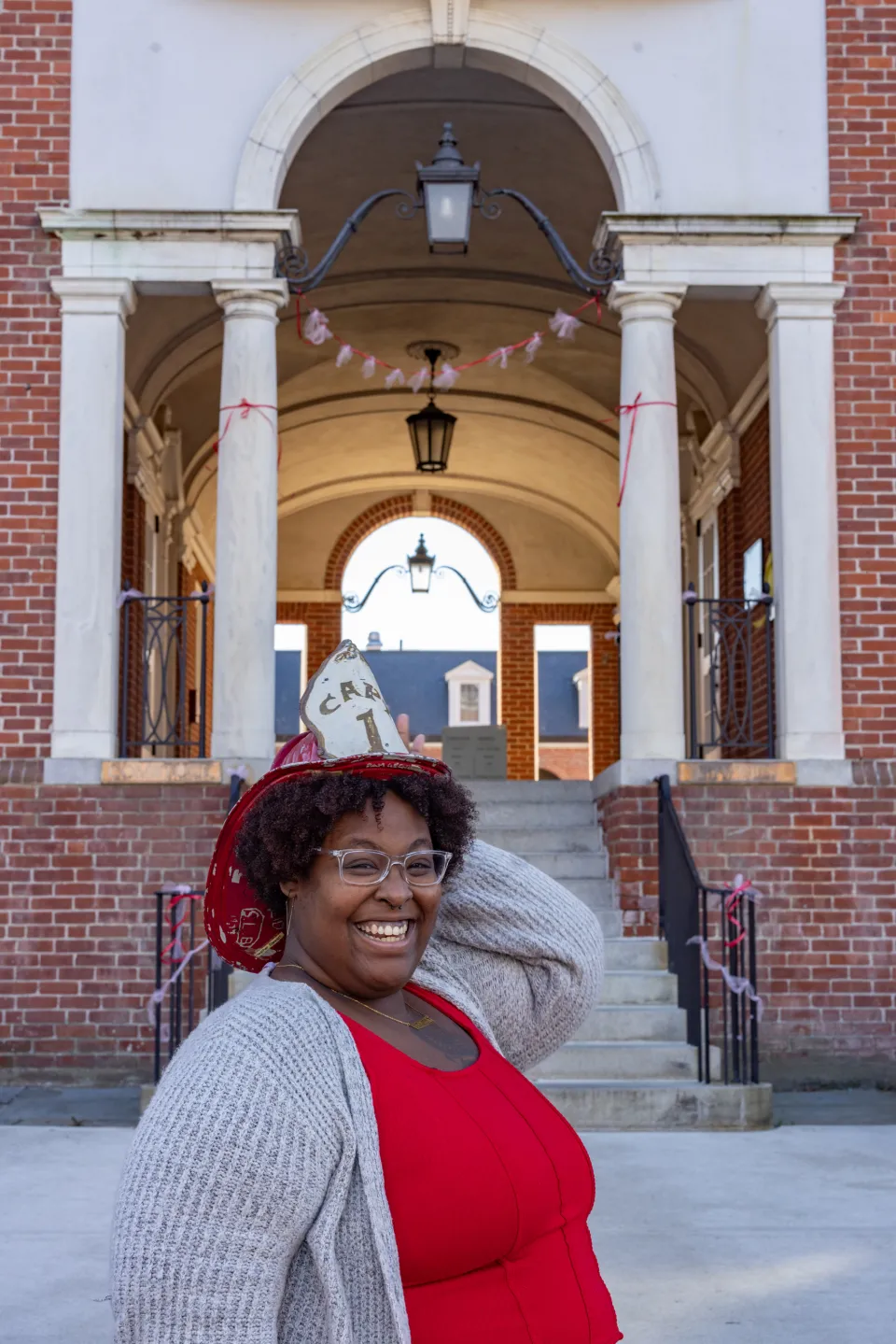 Diamond Jones, smiling, posing outside of Comstock and wearing an antique fire helmet