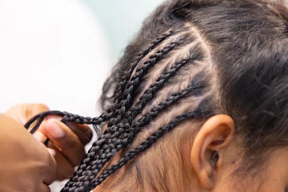 A close up of student researcher Kris Cheaye Braiding Gloriamar Esteves's hair