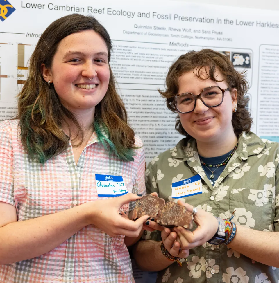 Steele and Wolf smile at the camera while holding up rock specimens