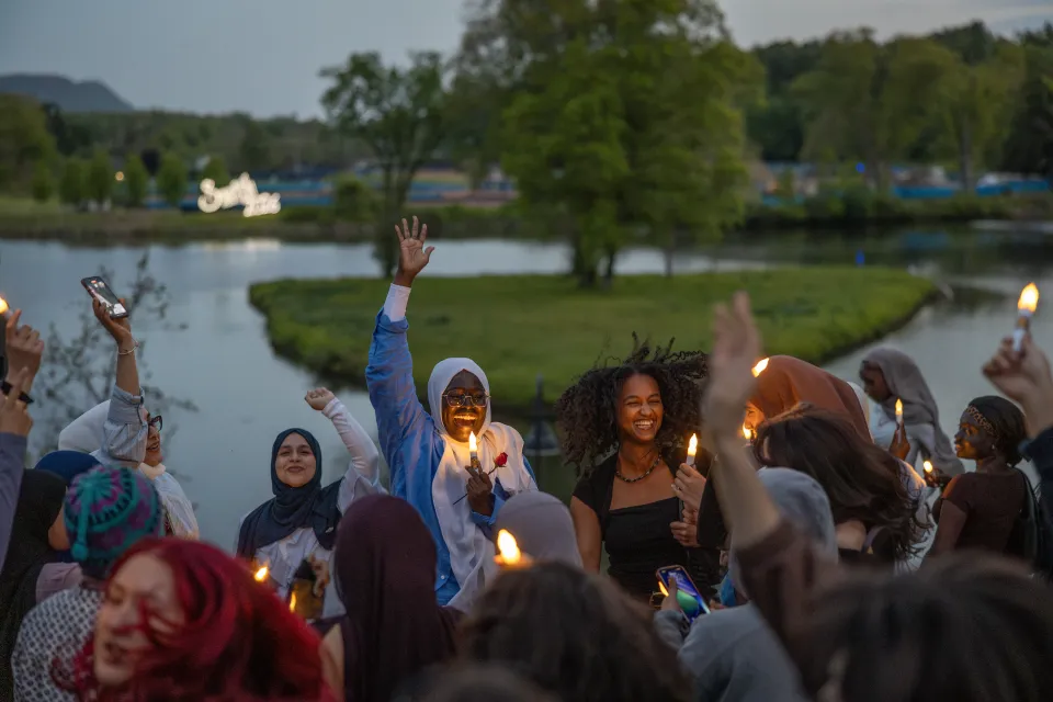 Students hold LED candles and cheer, while across the pond the "Smith 2026" sign lights up.