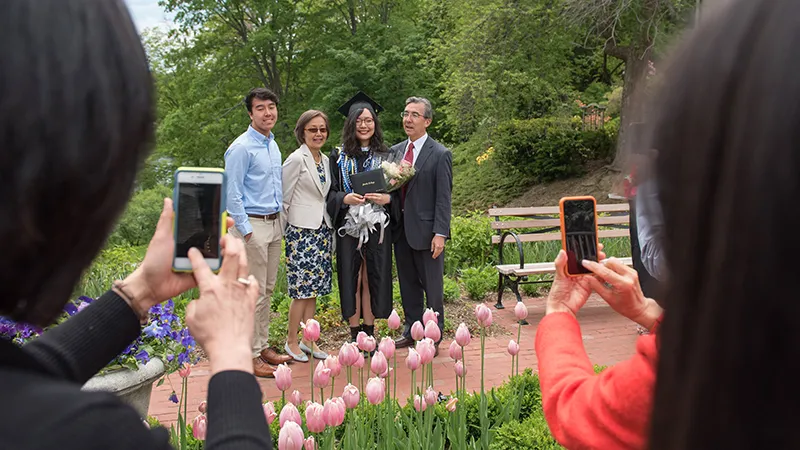 Photos being taken of a graduating senior with her parents