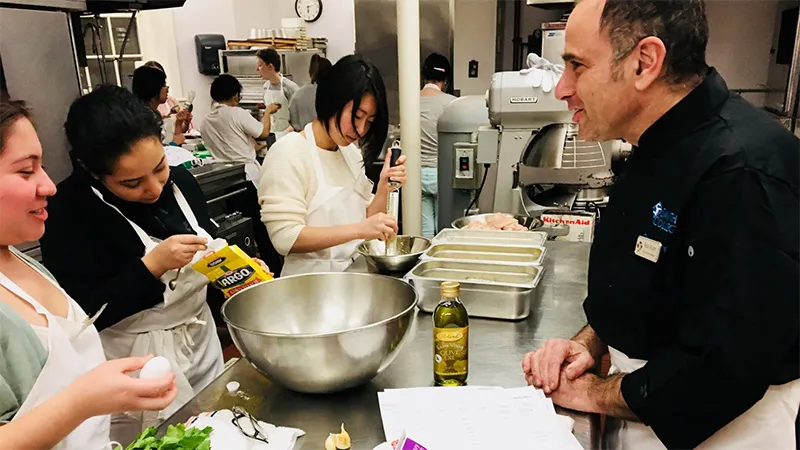 Students prepare a meal in a house kitchen