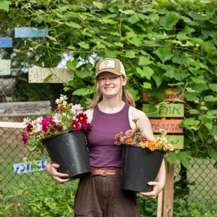 A student holding potted flowers during an internship.