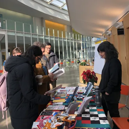 Students at a table in the Campus Center, looking at zines made by professor Kutlu's International Human Rights class