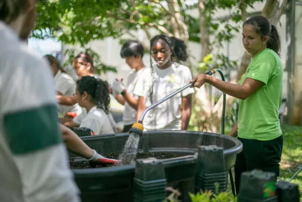 FAO Schwarz Fellow Julia Beyer '26 (at right) helps teens at an outdoor plant sale 