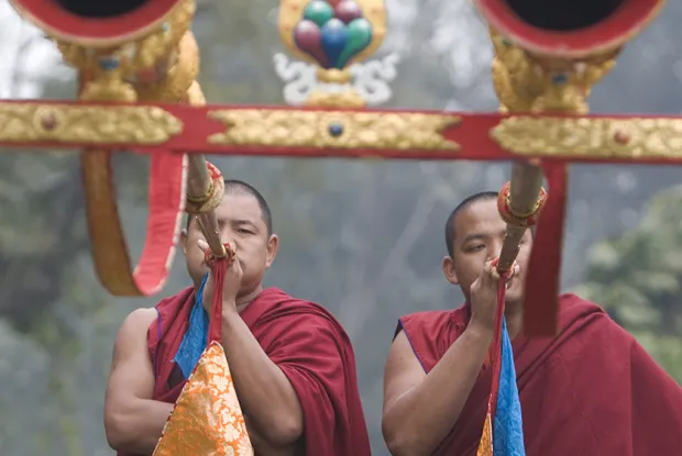 Two monks blowing into large horns, Tibet